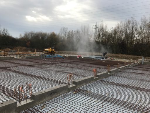 Chantier de construction avec fondations en béton et machines en activité.